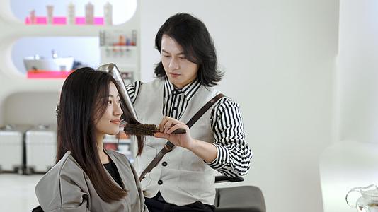 发型师为女顾客吹头发设计造型视频的预览图