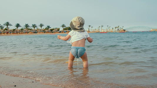 可爱的宝宝在度假胜地的海滩上散步视频的预览图