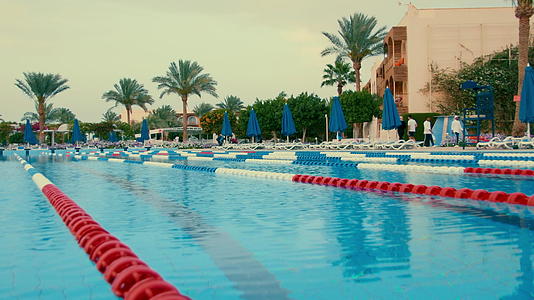 游泳池位于棕榈树背景的露天酒店视频的预览图