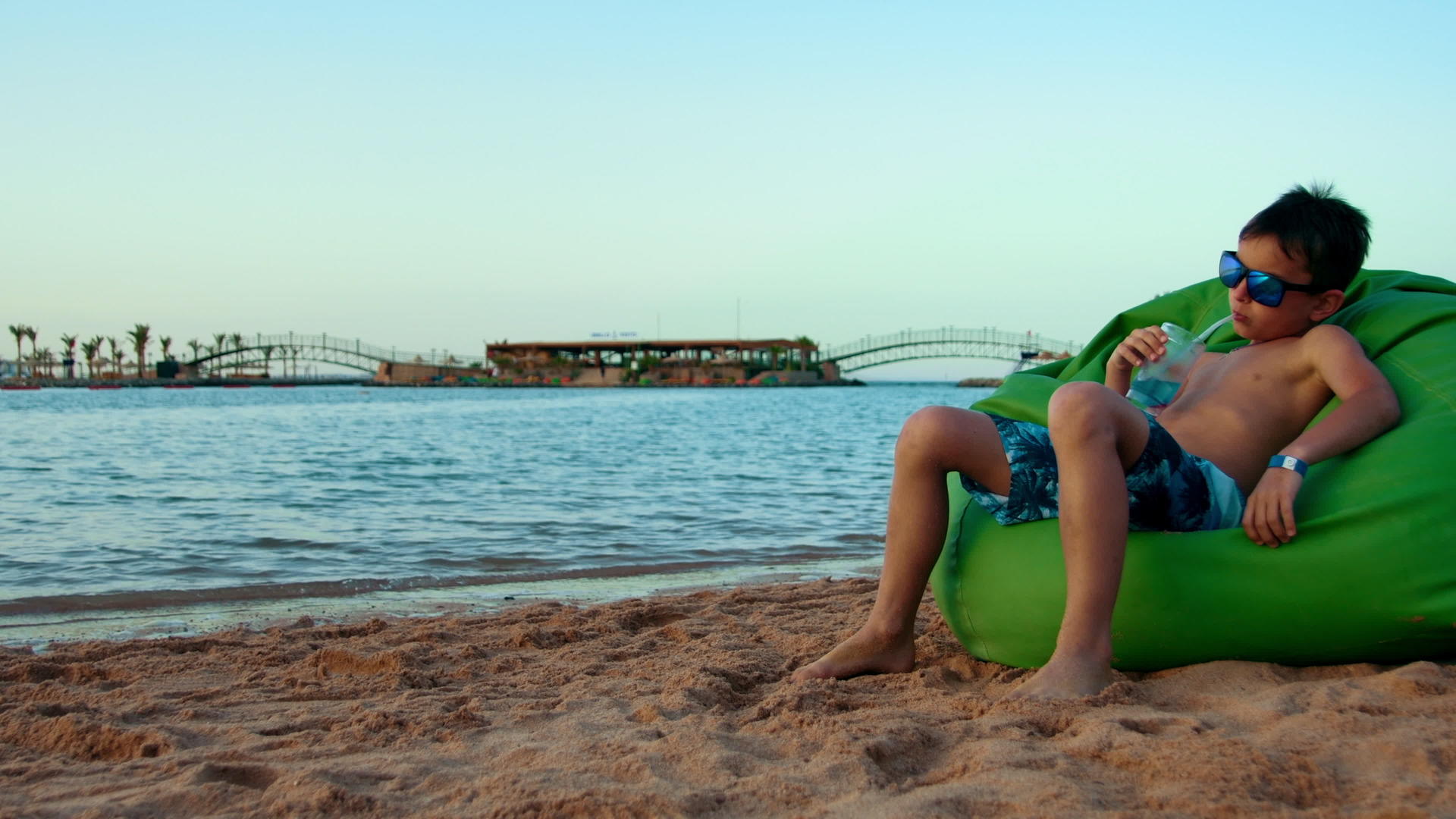 小男孩在海岸线上喝果汁休息视频的预览图