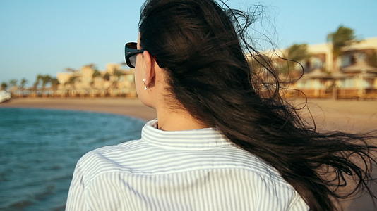 快乐的女人看着海滩海景的背影视频的预览图