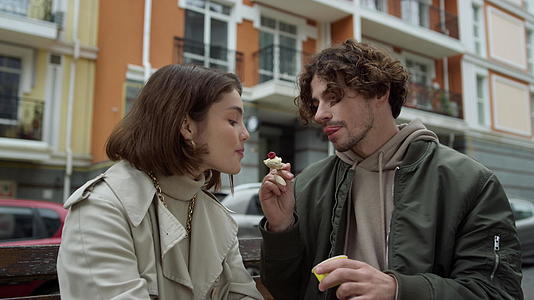 可爱的情侣在街上约会男人用城市背景喂养女人视频的预览图