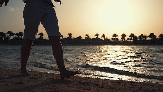 赤脚女孩在海边行走腿部特写背光剪影视频的预览图