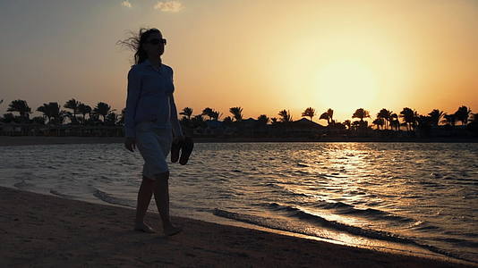 女性赤脚沿着日落海滩放松视频的预览图