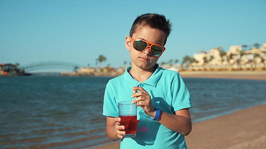 小男孩戴着墨镜在阳光明媚的海边享受暑假视频的预览图