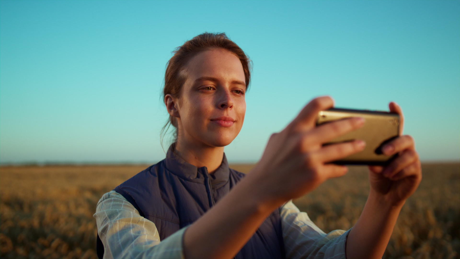 女性在金色农田景观中拍摄田野照片视频的预览图