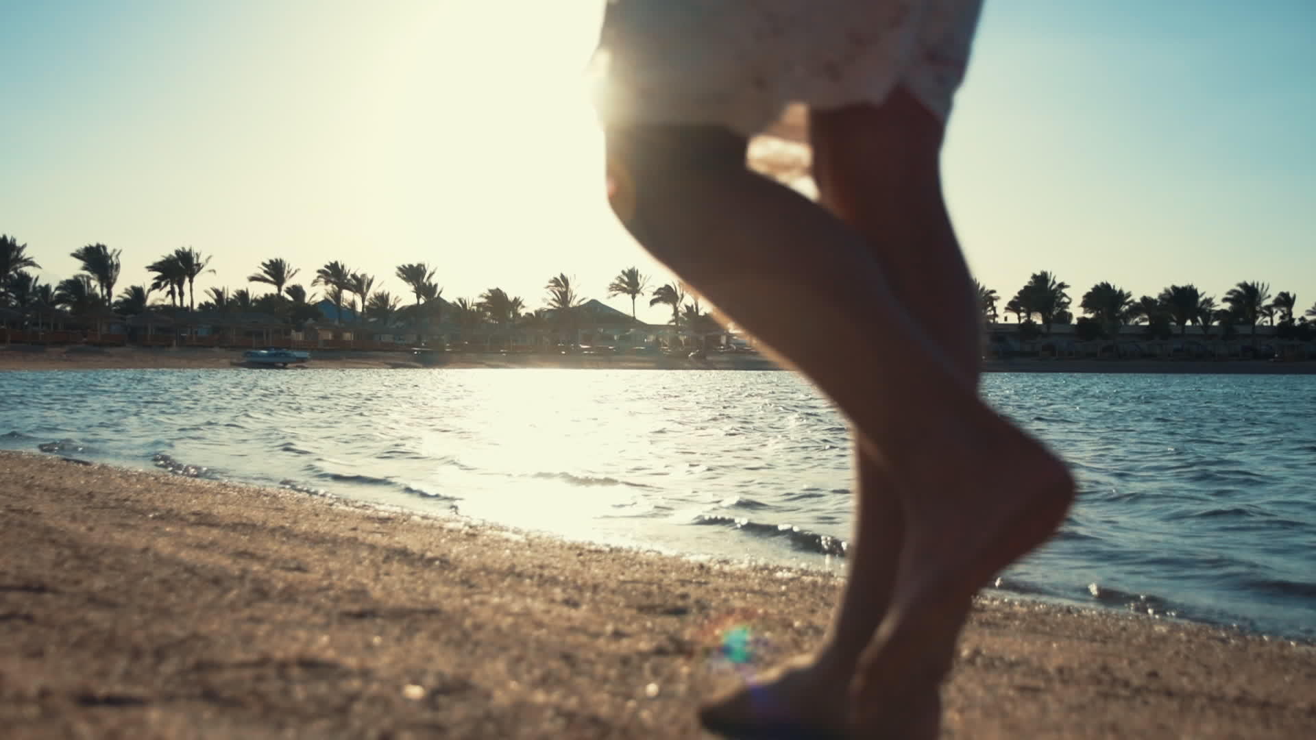 小女孩踩着脚在阳光明媚的海滩上走着腿视频的预览图