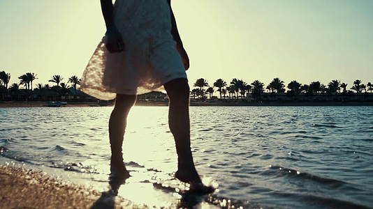 小女孩在日出时在海水中行走的腿部特写镜头视频的预览图