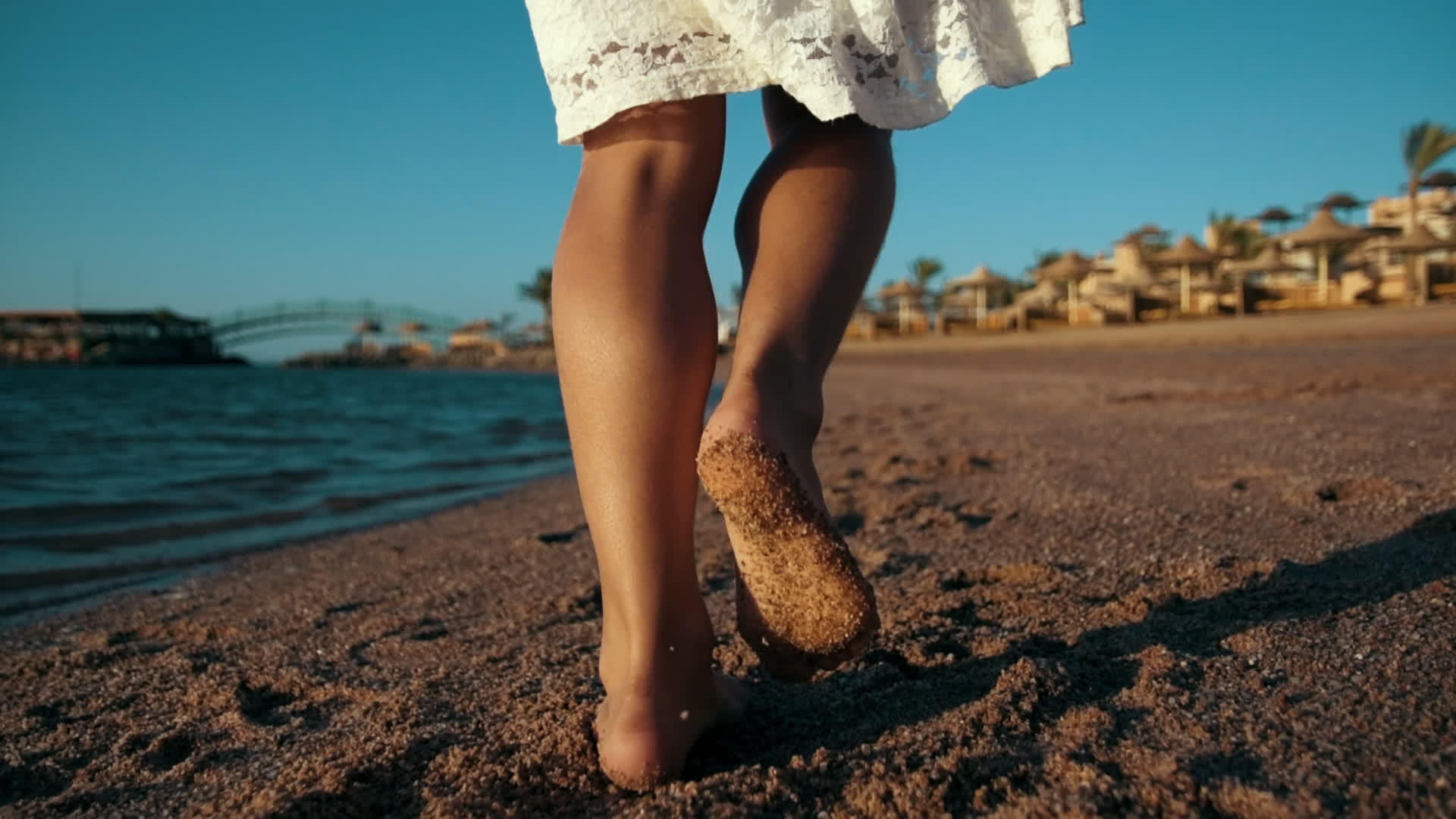 暑假期间年轻女孩沿着海滩海岸走腿视频的预览图