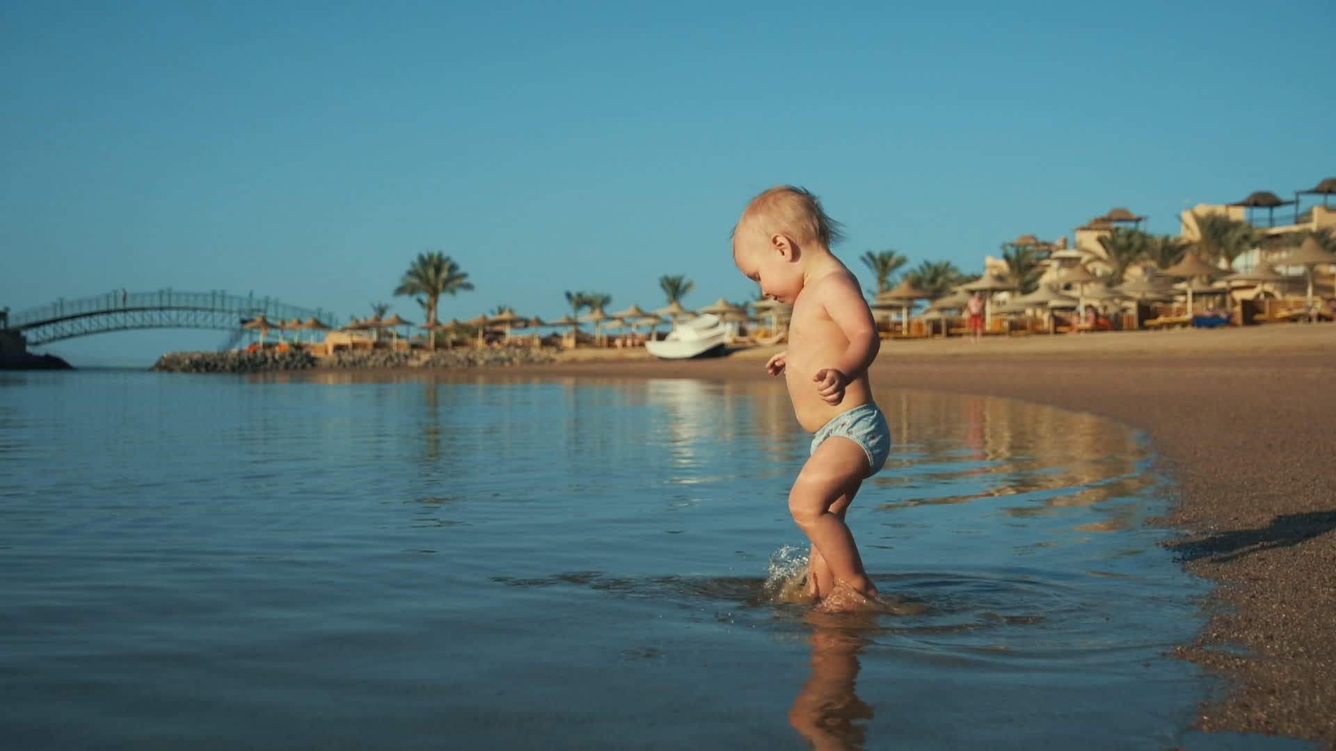 可爱的宝宝在温暖的海滩上泼水视频的预览图
