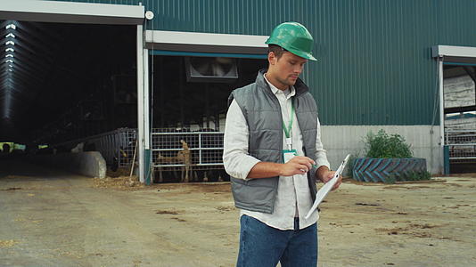 监督员拿着剪贴板独自在现代牲畜牛棚做笔记视频的预览图