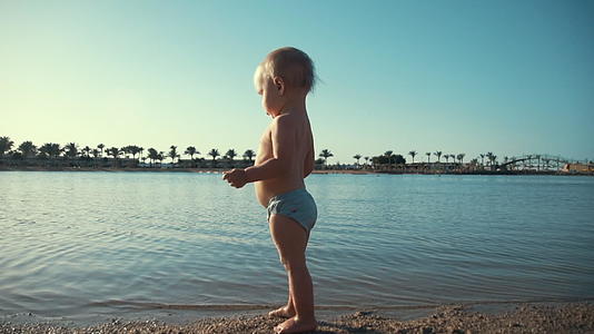 可爱的宝宝在夏天的海滩上玩耍视频的预览图
