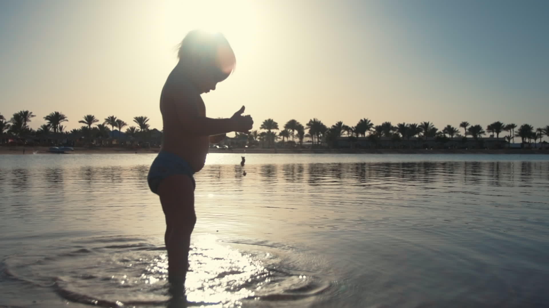 可爱的宝宝在日落海滩玩水视频的预览图