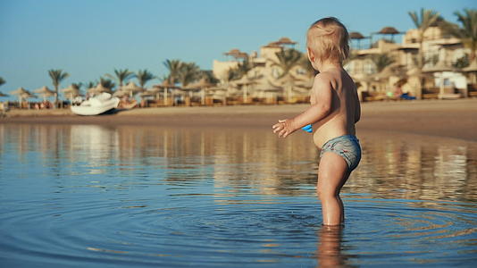 快乐的小男孩在海边玩水视频的预览图