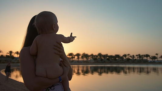 年轻的母亲和婴儿以及可爱的婴儿在度假胜地享受美丽的日落视频的预览图