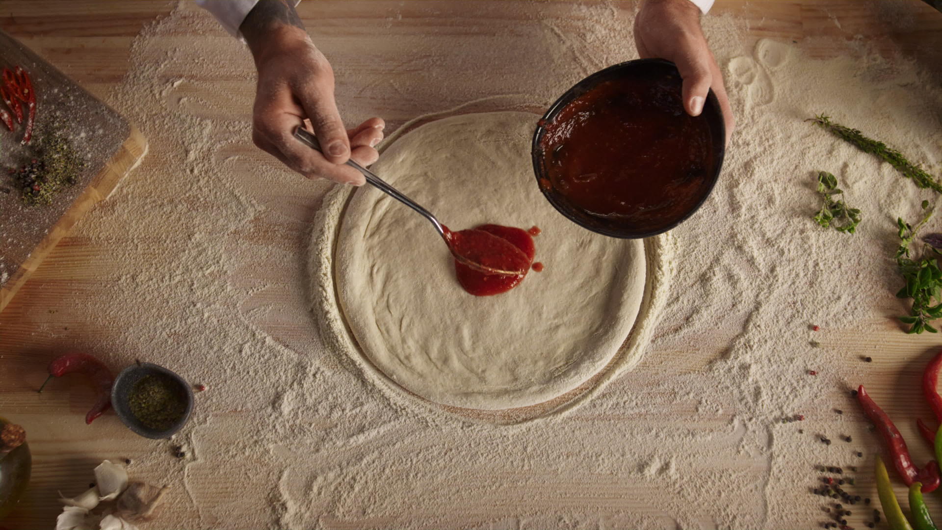 厨师在披萨上涂番茄酱视频的预览图