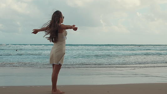 快乐的年轻女孩在海滩上放松张开双臂视频的预览图