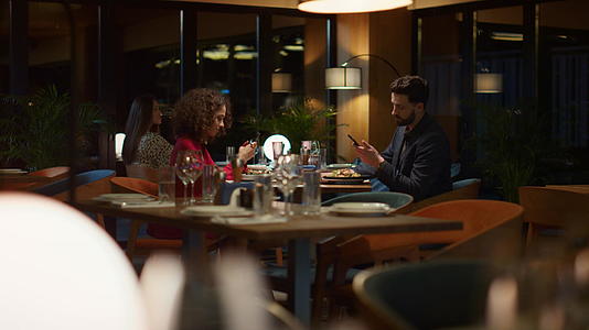 忙碌的夫妇在晚上餐厅约会时发短信电话移动设备视频的预览图