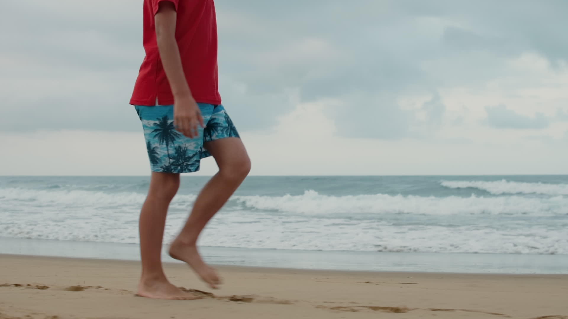 小男孩在海滩上享受暑假腿部特写视频的预览图