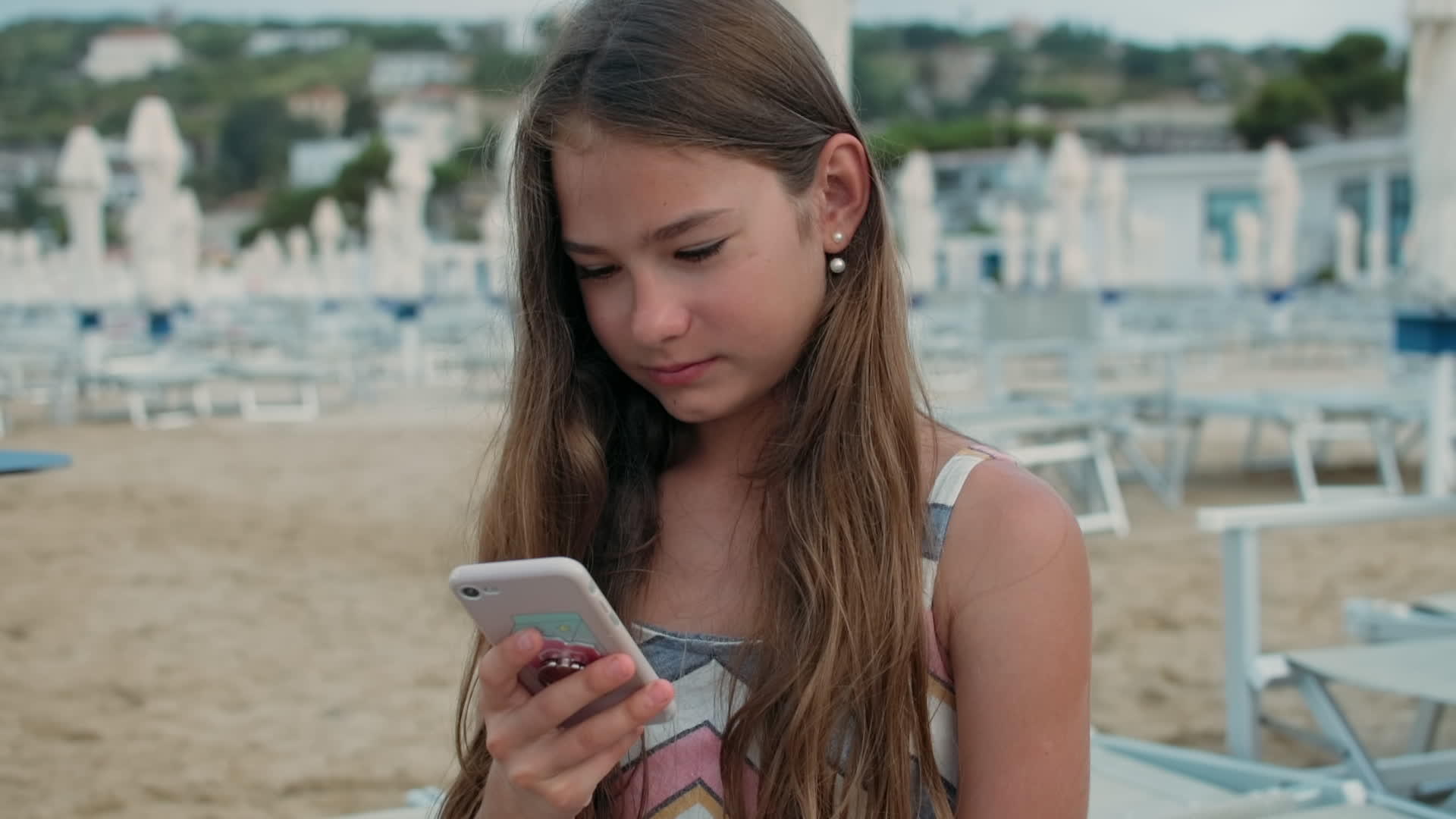 小女孩拿着手机在海边看信息视频的预览图