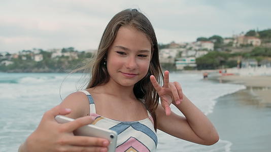 快乐的女孩在海边度过时光用手机自拍视频的预览图