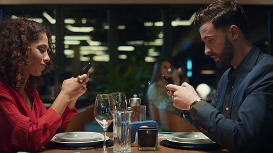 餐厅晚餐约会时的数字情侣冲浪电话视频的预览图