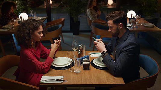 情侣们在浪漫的夜晚约会时在高档餐厅的餐桌上在线订购食物视频的预览图