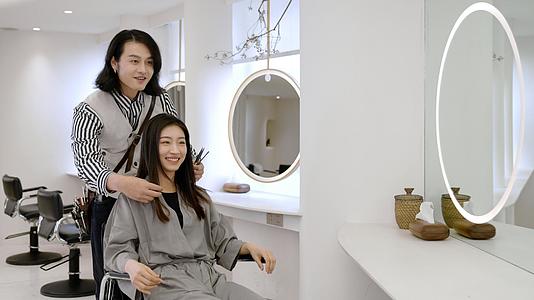 剪完头发后发型师和女顾客一起看效果视频的预览图