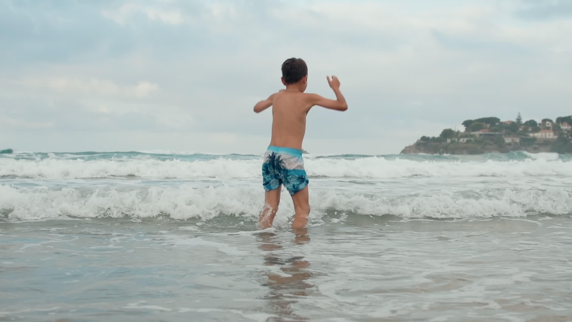 快乐的男孩在海岸线上玩得很开心视频的预览图