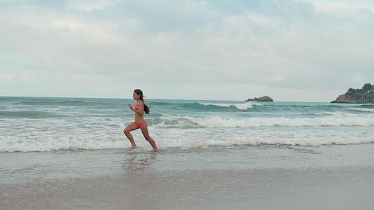 快乐的女孩在海滩上奔跑视频的预览图