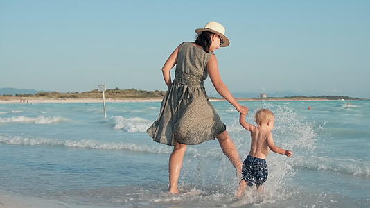 快乐的母亲和儿子在海边散步视频的预览图