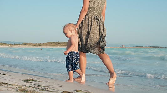 可爱的宝宝和妈妈在海滩上散步视频的预览图
