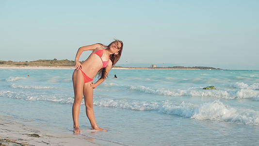 小女孩在沙滩上做拉伸运动视频的预览图