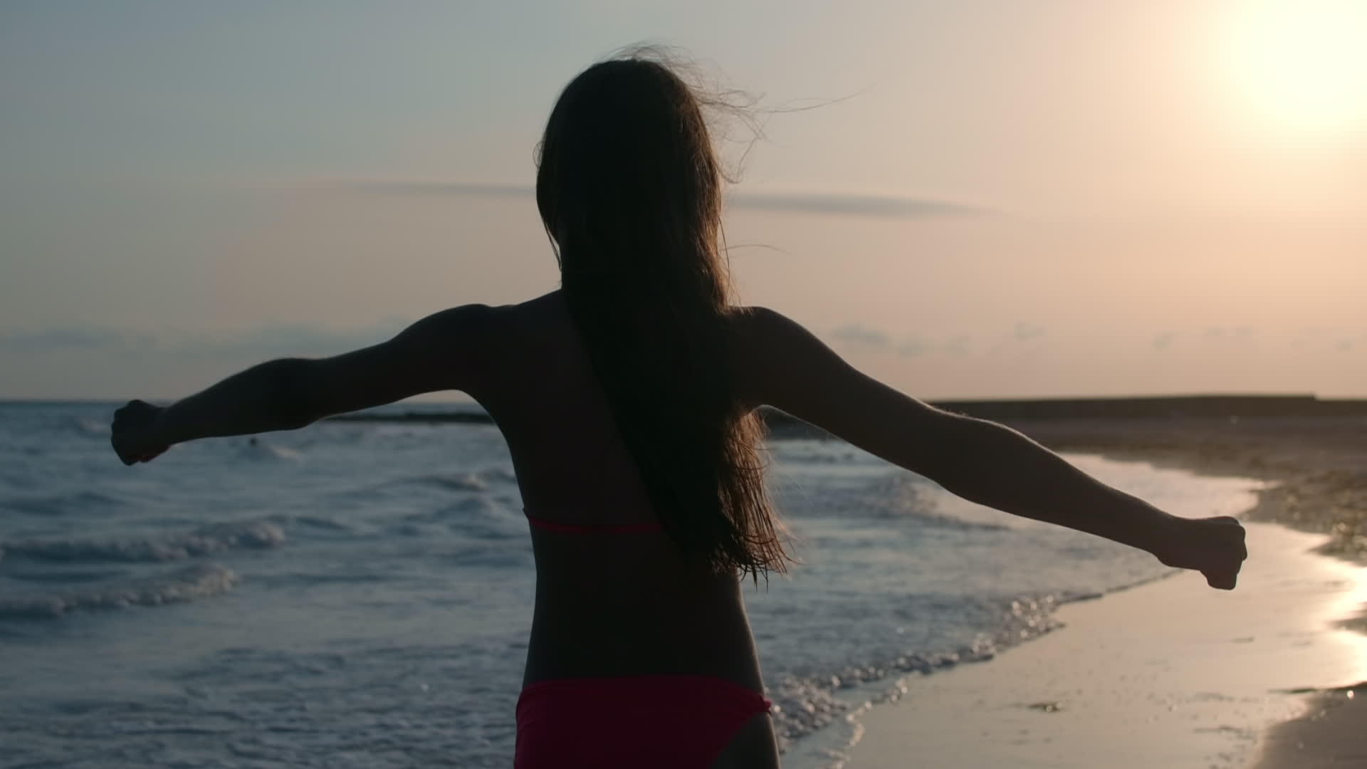 在沙滩上美丽的女孩用背光锻炼背部视频的预览图