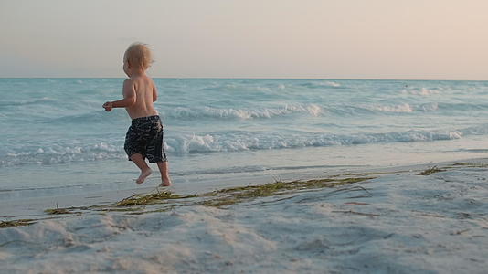 快乐的宝宝在海滩上快乐地奔跑视频的预览图