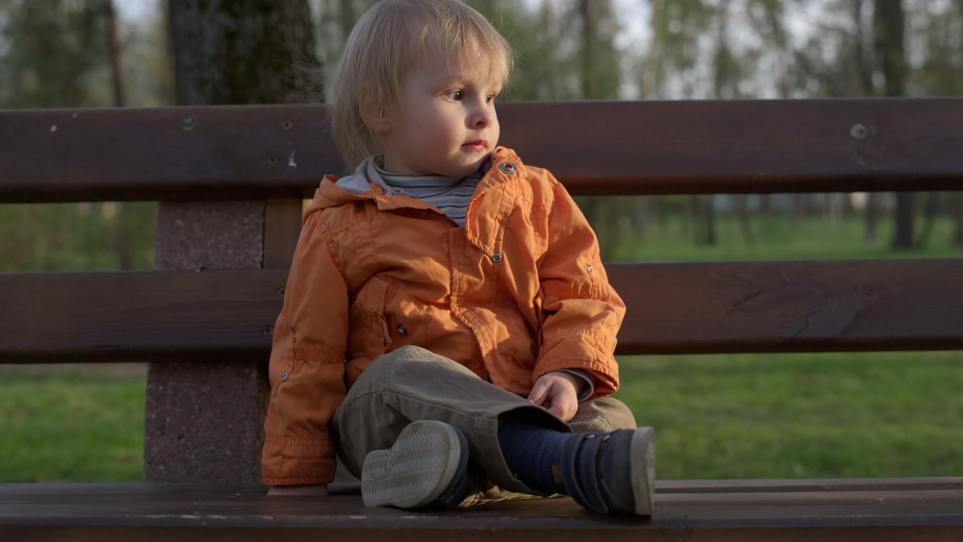 小男孩坐在公园的长椅上视频的预览图