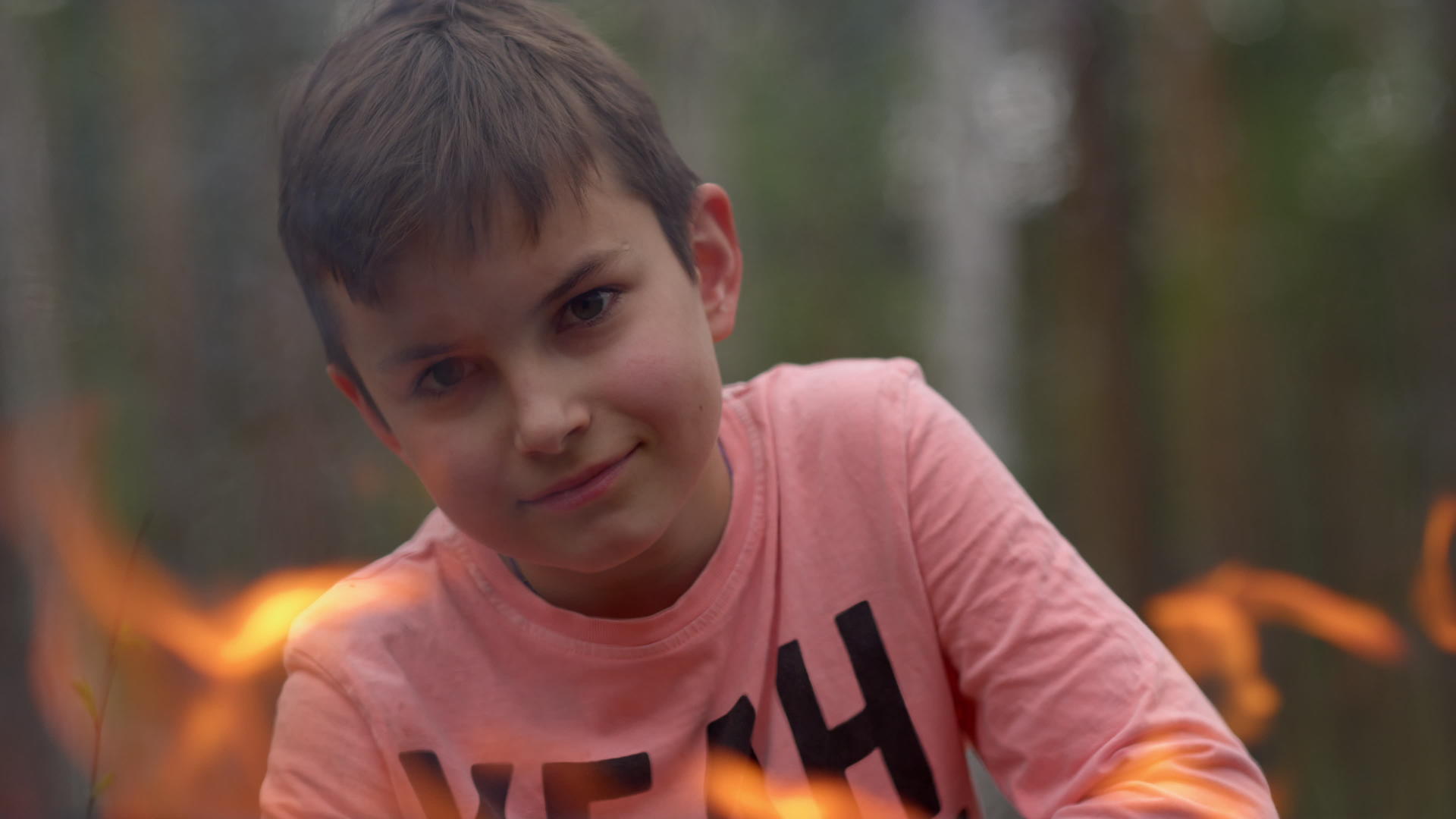 在森林里小男孩透过火焰对着镜头微笑视频的预览图