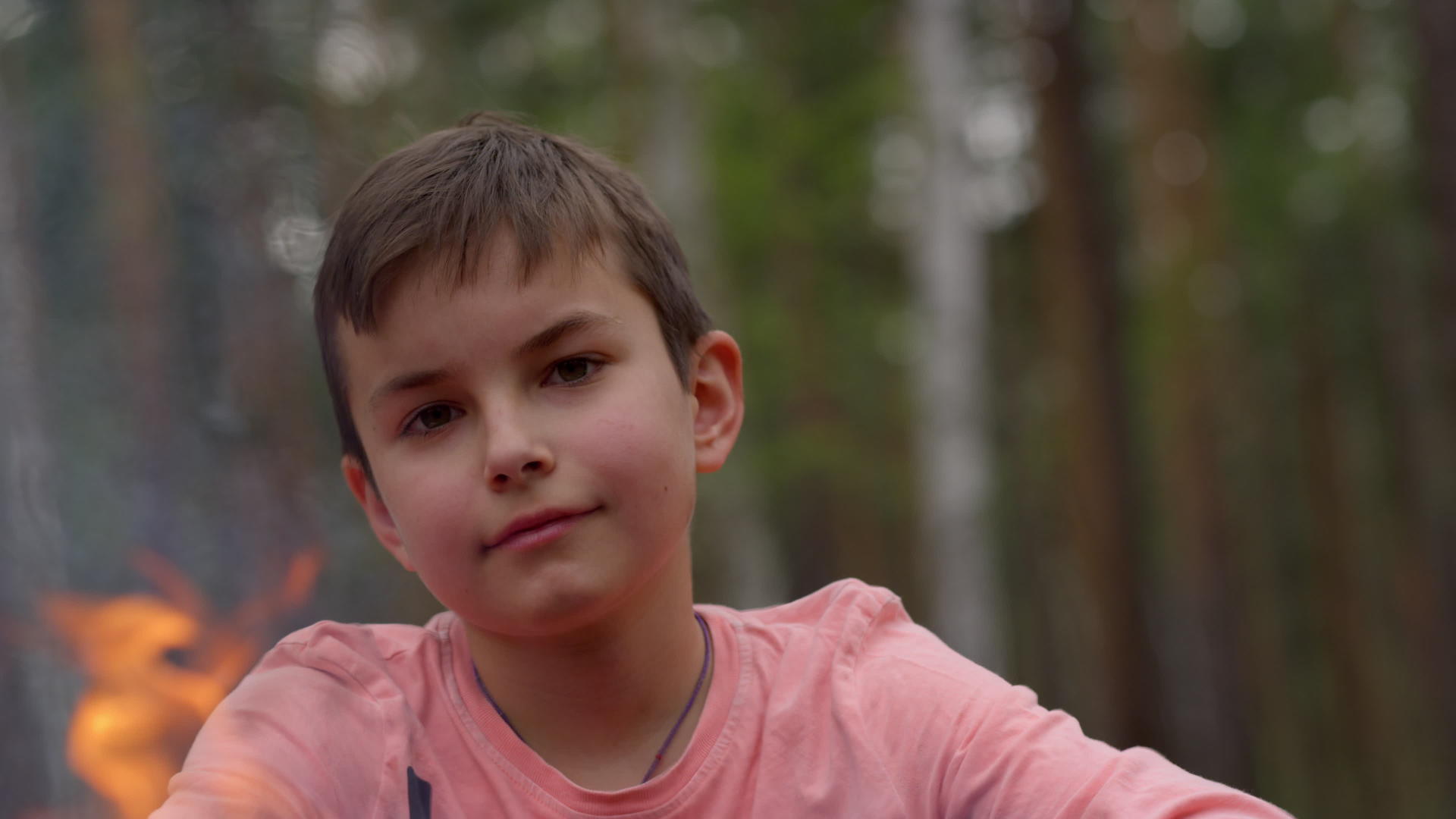 可爱的小男孩在森林营火附近微笑着面对镜头视频的预览图