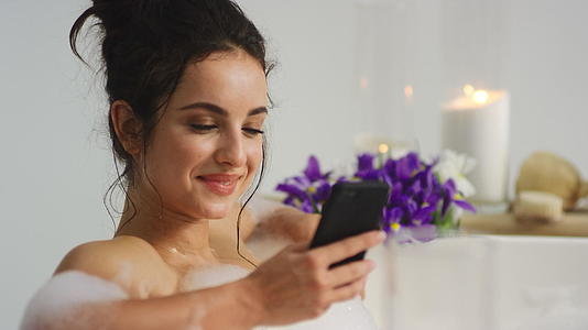 女性在浴缸中使用智能手机接收信息视频的预览图