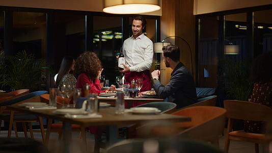 在夜间餐厅约会时服务员将酒瓶倒在花哨的情侣桌上视频的预览图
