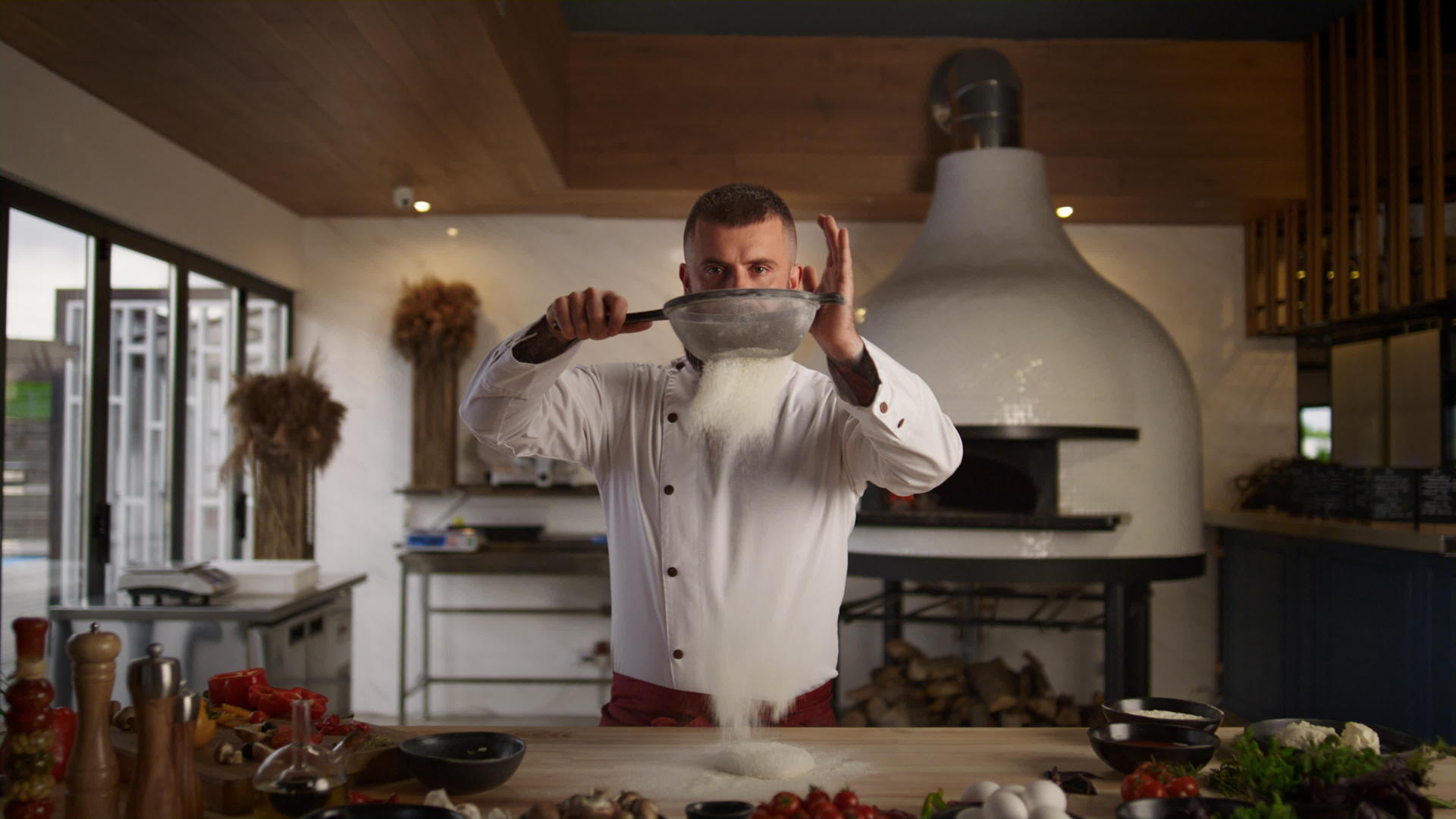 英俊的厨师在厨房里使用筛子面粉视频的预览图