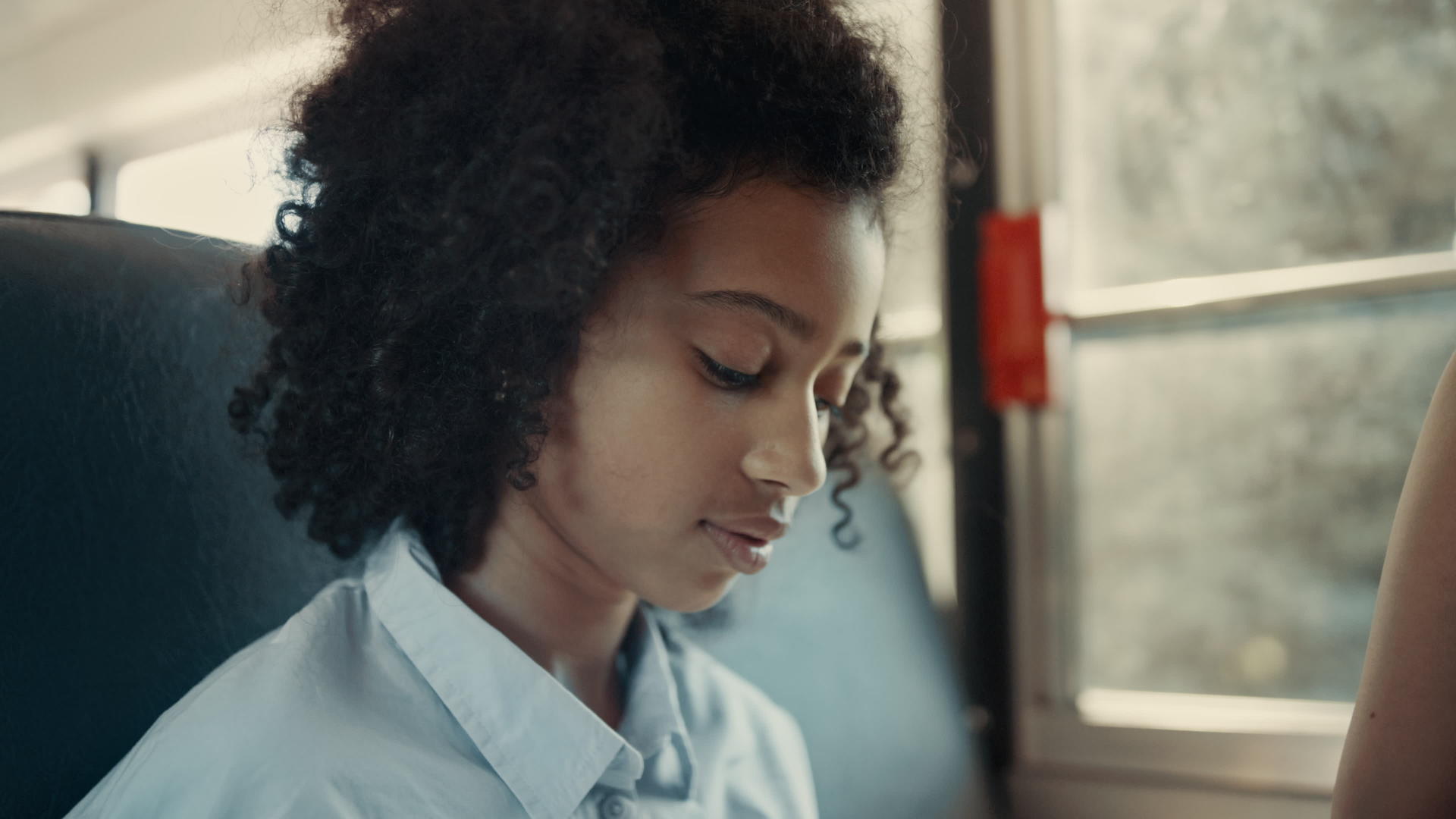 非裔美国女学生在校车上近距离观看相机视频的预览图