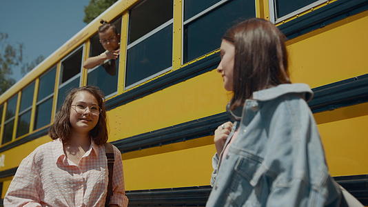 两个开朗的女孩在校车上聊天视频的预览图