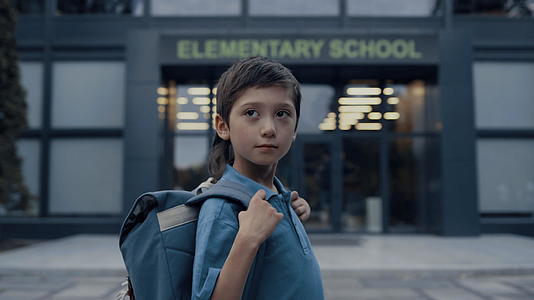 可爱的小男孩站在学校大楼附近视频的预览图