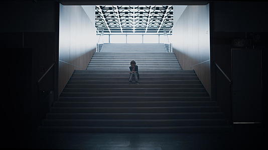 悲伤的男孩剪影独自坐在楼梯上视频的预览图