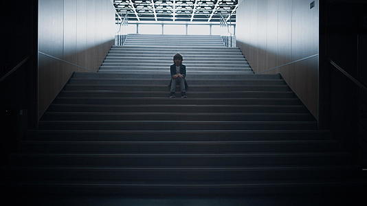 不快乐的小学生独自坐在楼梯上视频的预览图