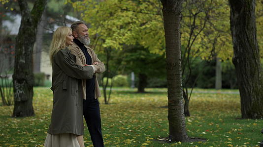 秋天的公园一对美丽的夫妇沿着小路慢慢地走着视频的预览图