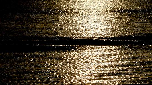低关键光、波浪、平稳滚动和日落反映在水中视频的预览图