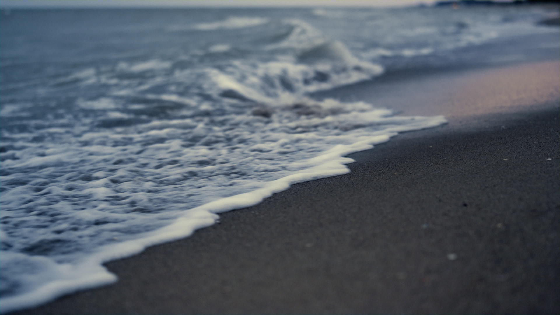 夕阳的傍晚沙滩上的海浪拍打着沙子视频的预览图