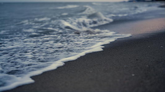 夕阳的傍晚沙滩上的海浪拍打着沙子视频的预览图